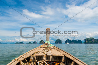 close-up of a Thai wooden boat sailing to beautiful rocks at sea
