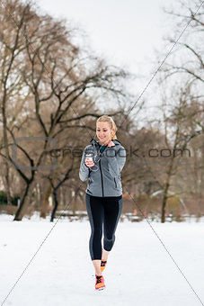 Woman running down a path on winter day in park