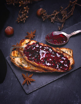 toast of white bread with raspberry jam on a black surface