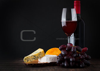 Bottle and glass of red wine with cheese selection
