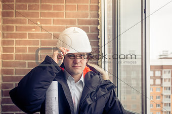 Business man construction engineer worker in protective helmet and blueprints paper on hand at house building site. Soft focus, toned.