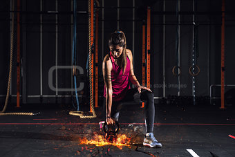 Athletic girl works out at the gym with a fiery kettlebell