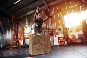 Athletic man does box jump exercises at the gym