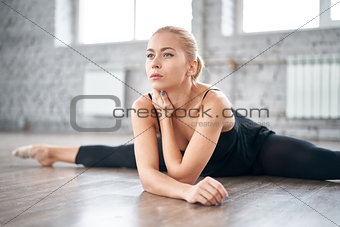 Slim thoughtful woman stretching her body in the gym