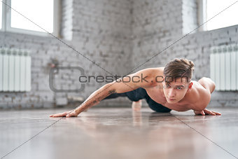Athletic young man doing push ups on the floor