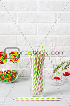 Glass with striped green pink drinking straws brick wall backgro