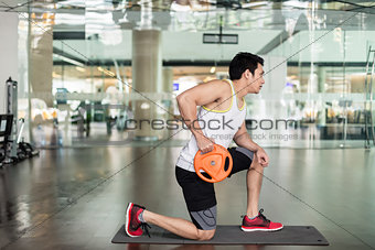 Fit young man exercising with a weight plate during upper-body workout