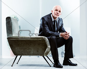 Pensive senior businessman sitting in an armchair