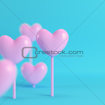 Pink hearts on a stick on bright blue background in pastel color
