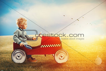 Child with car plays in a green field