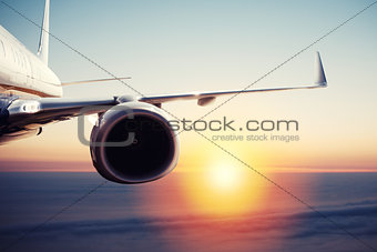 Aircraft flight over the clouds during sunrise