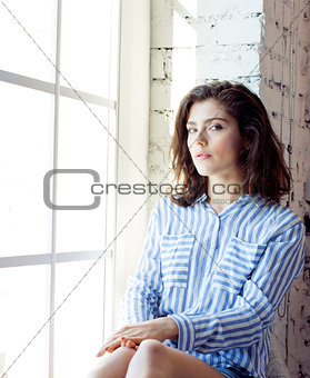 young pretty brunette woman in her bedroom sitting at window, ha