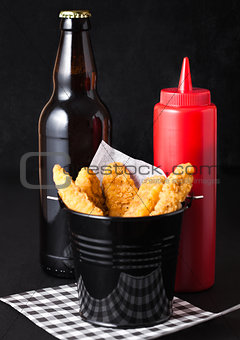 Fried chicken dippers in black bucket with beer