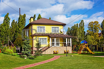 Exterior of beautiful house with green yard and children playgro