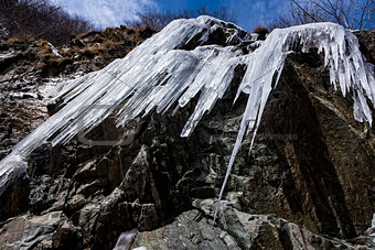 Dangerous immense icicles formed along a mountain valley and hanging above a road