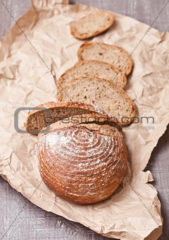 Freshly baked bread loaf with pieces on wood board