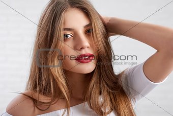 Attractive Caucasian female model in white top wearing eye make up and red lipstick