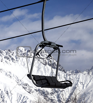 Chair lift in snowy mountains at nice sun day