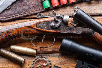 The hunting rifle, cartridge belt,binoculars on a wooden table