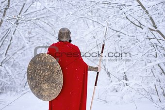 Careful spartan warrior in cold snowy forest.