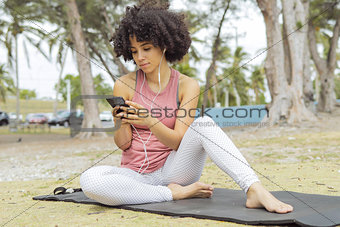 Chilling black girl using phone on mat