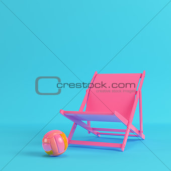 Pink beach chair with volleyball ball on bright blue background 