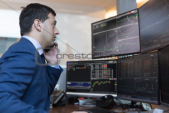 Stock broker trading online watching charts and data analyses on multiple computer screens.