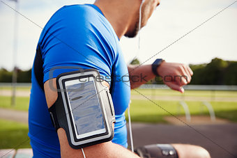 Male athlete wearing smartphone armband checking smartwatch