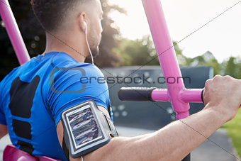 Young male athlete using outdoor gym, over shoulder view