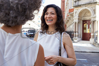 Two female friends talking in the street, close up