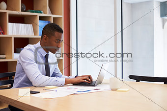 Young black businessman working alone in an office, close up