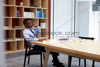 Young black businessman using smartphone in the boardroom