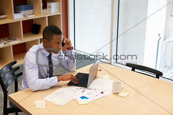 Young black man using smartphone in a boardroom, elevated view