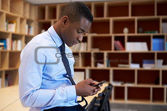 Young black man using smartphone in a boardroom, close up