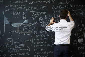 Young man writing on blackboard