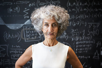 Middle aged academic woman standing in front of blackboard