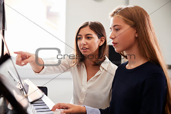 Female Pupil With Teacher Playing Piano In Music Lesson