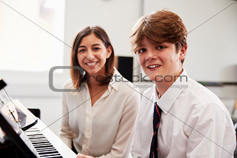 Portrait Of Pupil With Teacher Playing Piano In Music Lesson