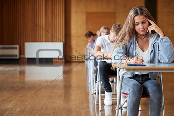 Group Of Teenage Students Sitting Examination In School Hall
