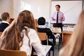 Teenage Students Listening To Male Teacher In Classroom