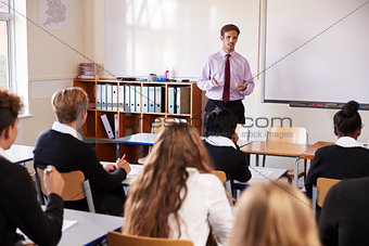 Teenage Students Listening To Male Teacher In Classroom