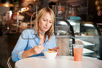 Woman In Coffee Shop Sitting At Table Eating Bowl Of Soup