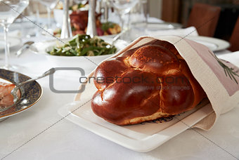 Challah bread on a table set for Jewish Shabbat, close up