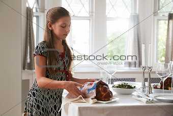 Girl covering challah bread on a table set for Shabbat meal