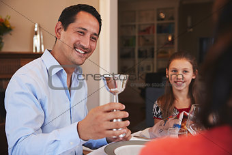 Jewish man holding kiddish cup blesses family at Shabbat