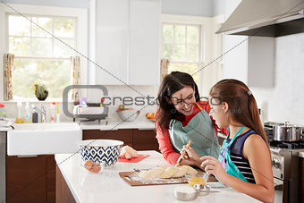 Jewish girl glazing plaited challah bread dough with her mum