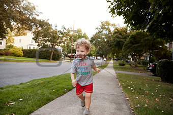 Toddler boy running in a quiet residential street