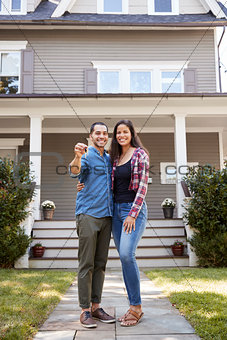 Portrait Of Couple Holding Keys To New Home On Moving In Day
