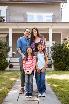 Portrait Of Smiling Family Standing In Front Of Their Home
