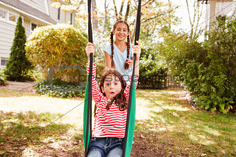 Two Sisters Having Fun On Garden Swing At Home